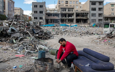 A man sits among buildings destroyed in a joint attack